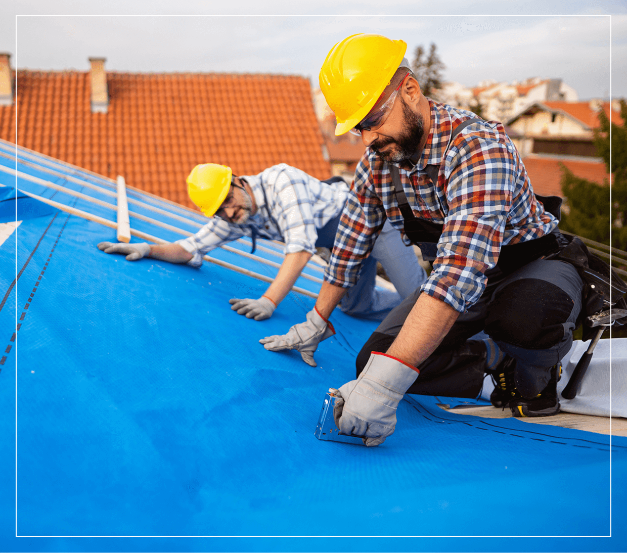 Workers installing roof with blue tarp.