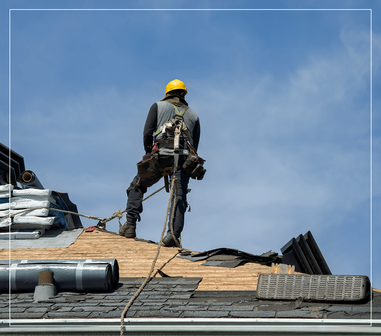 Worker on roof with safety gear.